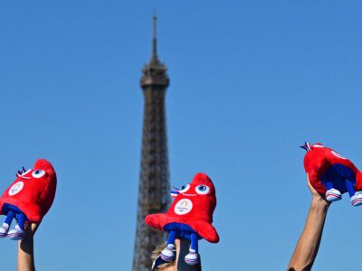 Trois peluches des Phryges brandies devant la Tour Eiffel